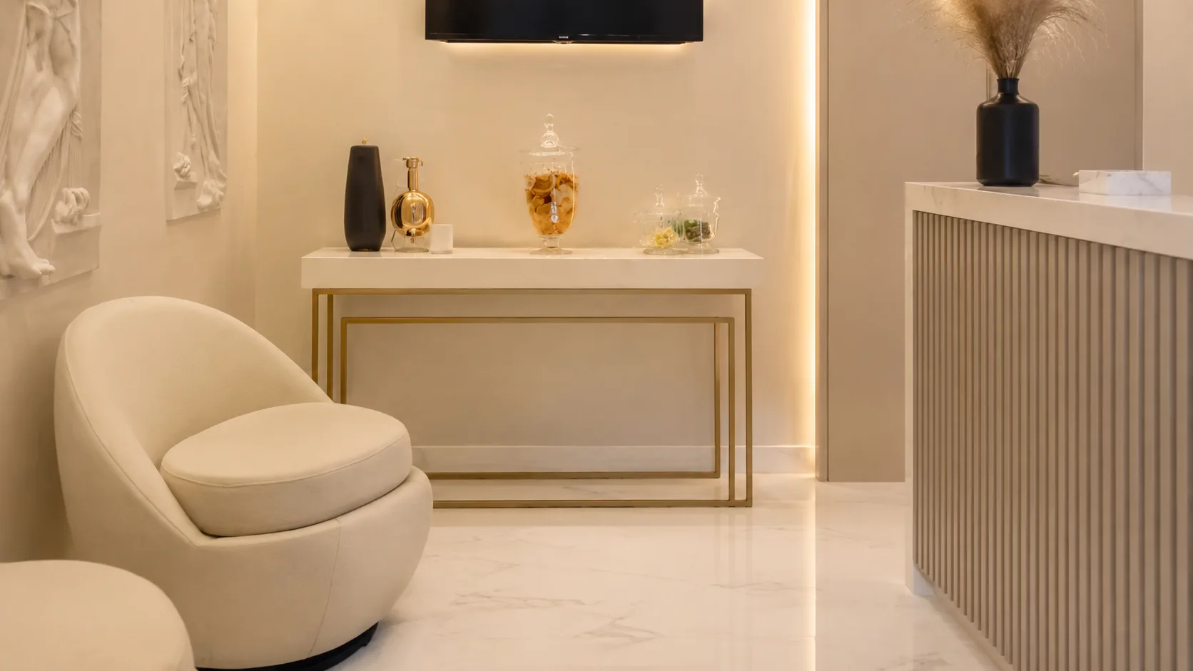 Sala de espera com poltrona, aparador e esculturas em relevo